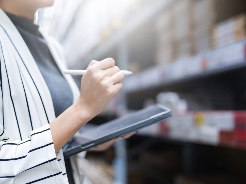 close up female business owner hand hold tablet device checking inventory stock at shop warehouse distributor factory business ideas concept