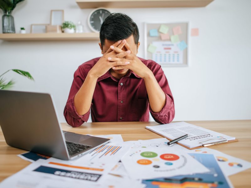 Man working with laptop and paperwork with stress